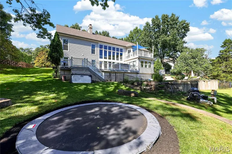 Rear exterior with siding, multi-level decking, extensive windows, and a manicured lawn — 17711 Birch Leaf Court, Chesterfield, MO 63005