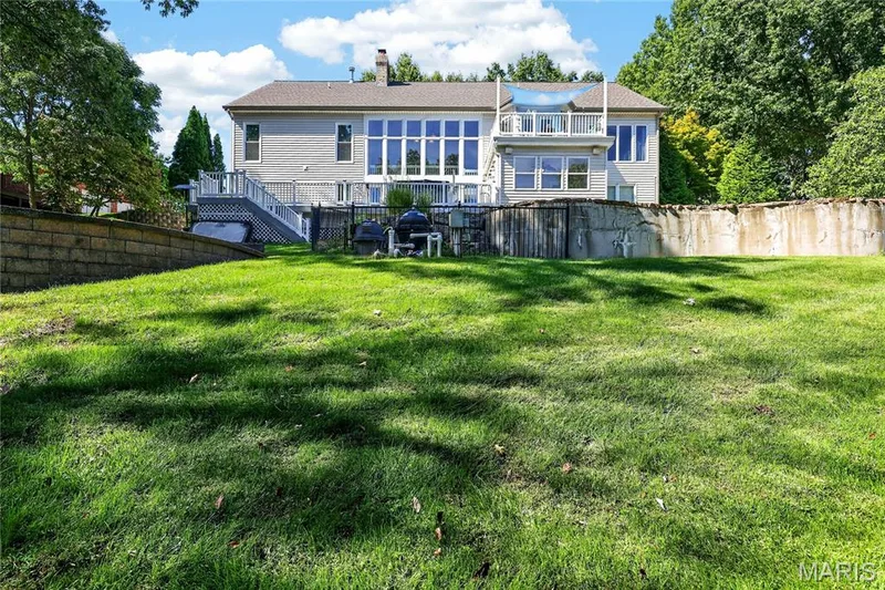 Multi-level exterior featuring extensive window coverage, a balcony, and a ground-level deck — 17711 Birch Leaf Court, Chesterfield, MO 63005