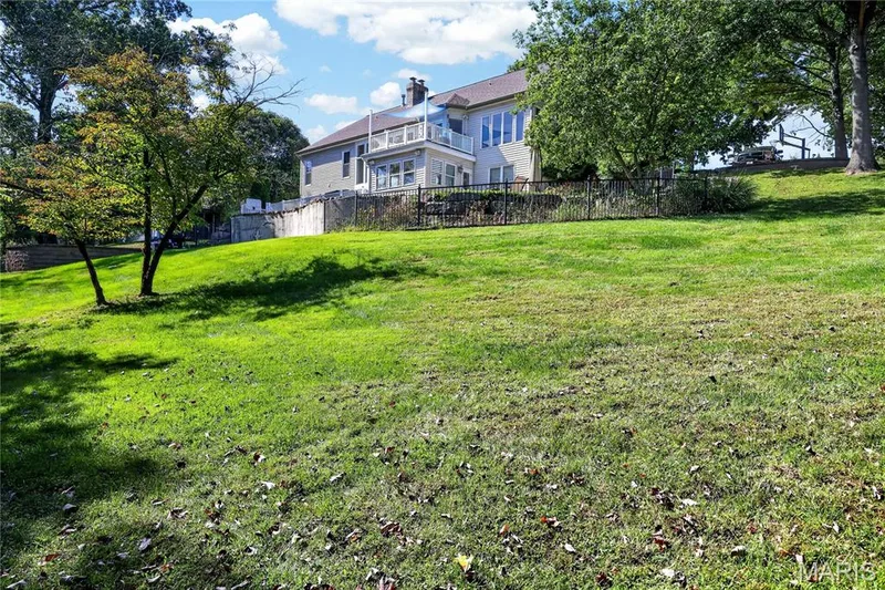 Expansive lawn with established trees, featuring a two-story residence with multiple windows and an upper-level balcony — 17711 Birch Leaf Court, Chesterfield, MO 63005