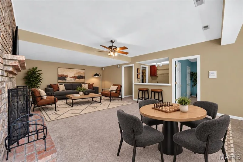 Full-height brick masonry fireplace with a stone hearth, ceiling fan, and built-in service bar with integrated counter seating — 17711 Birch Leaf Court, Chesterfield, MO 63005