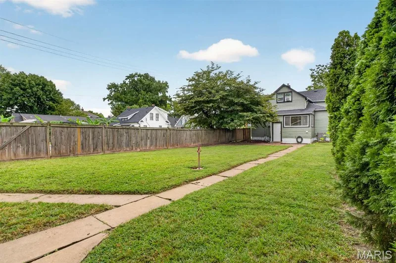 Expansive lawn with a concrete pathway between Main Home and Guest Quarters, mature trees, and a wooden privacy fence — 329 Houston Street, St Charles, MO 63301