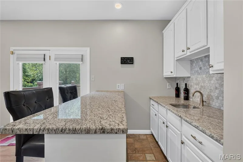 Bar area has granite counters, cabinets for storage, tile backsplash and sink. — 947 Crown Pointe Estates Drive, Wildwood, MO 63021