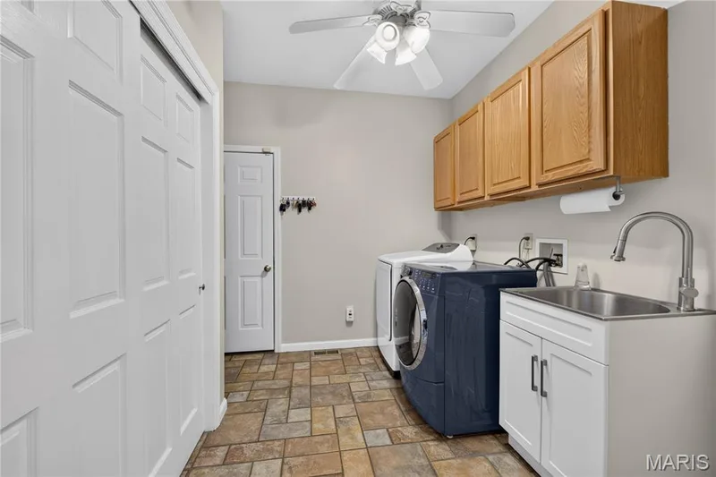 Main floor laundry opens to garage, has abundant storage and great stainless utility sink with storage cabinet below. — 947 Crown Pointe Estates Drive, Wildwood, MO 63021