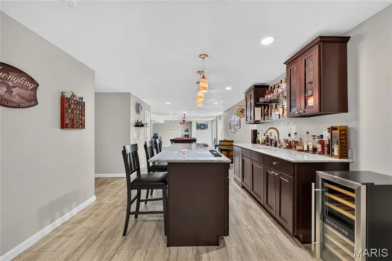 Lower level bar has granite counters, glass front cabinets, shelving to display beverages and sink. — 947 Crown Pointe Estates Drive, Wildwood, MO 63021