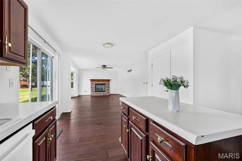 Wood-finish flooring throughout, bright white walls, and a brick-front fireplace with a wood mantle — 39 Green Pines Circle, St Peters, MO 63376