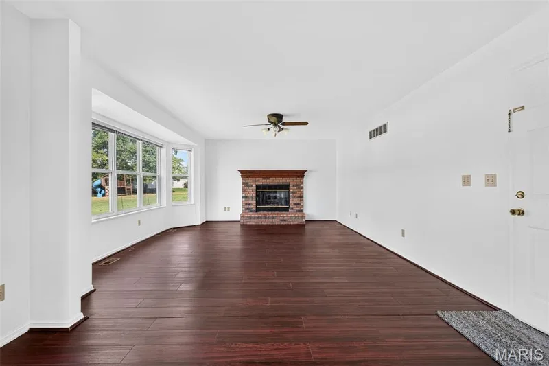 Rich wood-finish flooring complements the brick fireplace with a wood mantle — 39 Green Pines Circle, St Peters, MO 63376