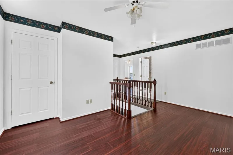 Wood-finish flooring with a dark stain, white paneled doors, white walls, and a ceiling fan with integrated lighting — 39 Green Pines Circle, St Peters, MO 63376
