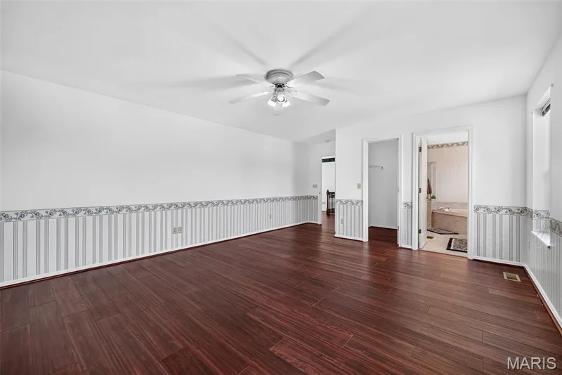 Wood-finish flooring, ceiling fan with light fixture, and an attached bathroom featuring a built-in tub — 39 Green Pines Circle, St Peters, MO 63376