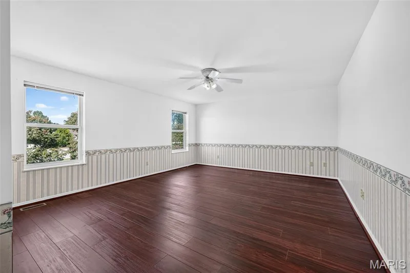 Dark wood-finish flooring with white walls and dual windows — 39 Green Pines Circle, St Peters, MO 63376