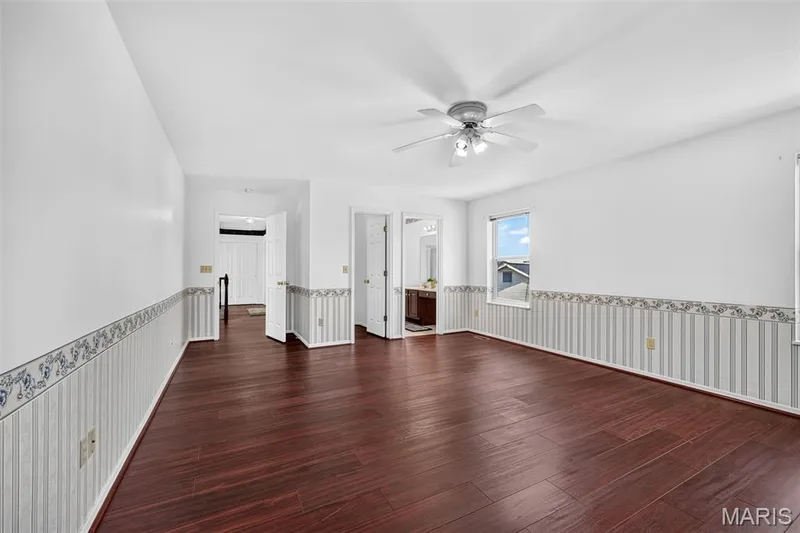 Spacious room featuring wood-finish flooring, a ceiling fan with integrated lighting, and multiple windows — 39 Green Pines Circle, St Peters, MO 63376