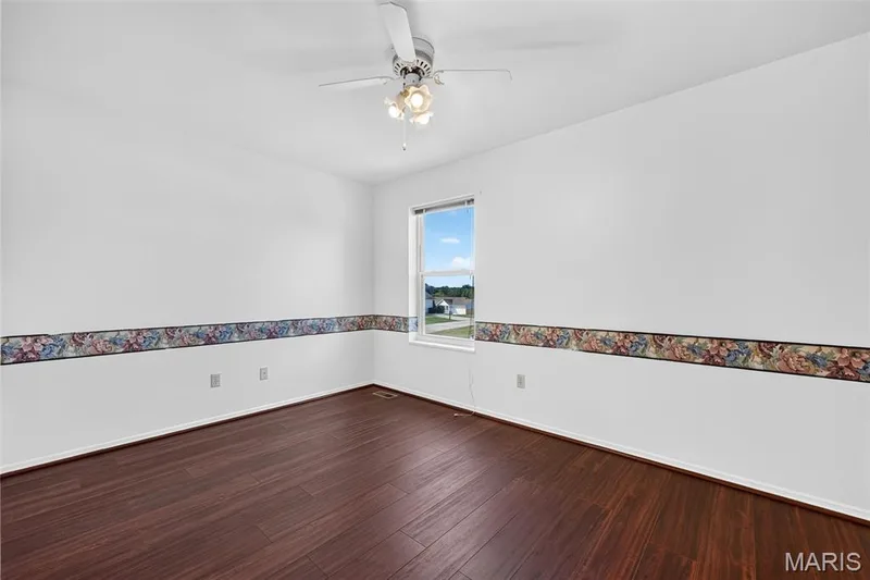 Wood-finish flooring with white baseboards, a white ceiling fan, and a single window — 39 Green Pines Circle, St Peters, MO 63376