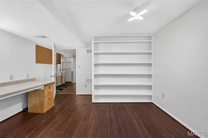 Wood-finish flooring throughout, featuring a built-in desk with drawers, white built-in shelving, and a ceiling-mounted light fixture — 39 Green Pines Circle, St Peters, MO 63376