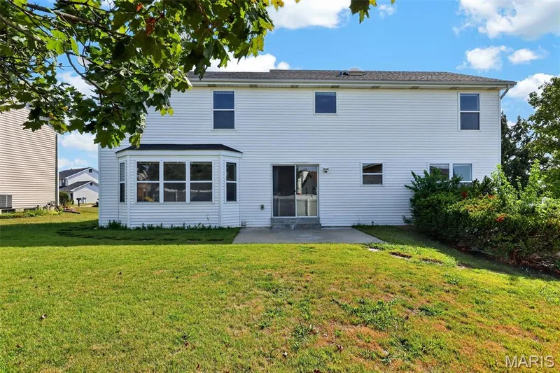 White-sided exterior featuring a bay window, concrete patio, and mature shrubbery — 39 Green Pines Circle, St Peters, MO 63376
