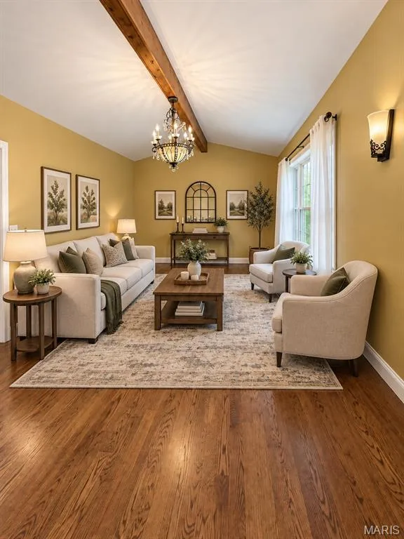 Vaulted ceiling with exposed wood beam, wood-finish flooring, chandelier lighting, and a large window. virtually staged — 3 Fairfax Drive, St Peters, MO 63376