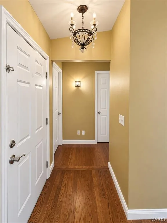 Hardwood flooring throughout, featuring a decorative chandelier and white trim — 3 Fairfax Drive, St Peters, MO 63376