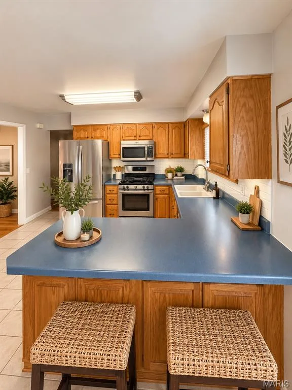 Kitchen featuring wood cabinetry, blue countertops, tile flooring, a stainless steel refrigerator, and a stainless steel range with an overhead microwave — 3 Fairfax Drive, St Peters, MO 63376