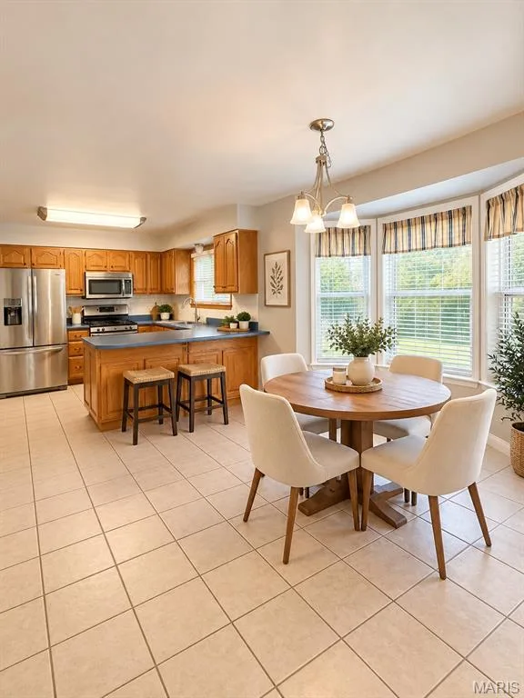Kitchen featuring wood cabinetry, stainless steel appliances, a kitchen island, and tiled flooring, virtually staged — 3 Fairfax Drive, St Peters, MO 63376