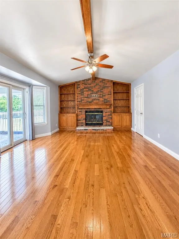 Hardwood flooring, brick fireplace with mantel, built-in shelving, ceiling fan, door to patio — 3 Fairfax Drive, St Peters, MO 63376