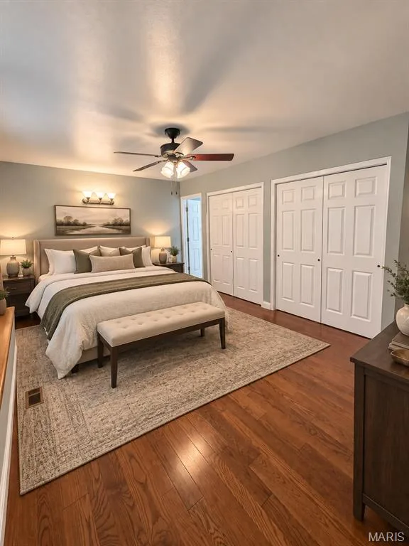 Wood-finish flooring with a ceiling fan, three paneled closet doors, and a wall-mounted light fixture, virtually staged — 3 Fairfax Drive, St Peters, MO 63376