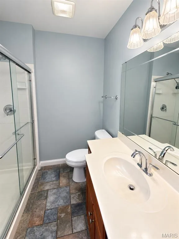 Glass-enclosed shower, single vanity with integrated sink, wood-finish cabinetry, and multi-toned floor tile — 3 Fairfax Drive, St Peters, MO 63376