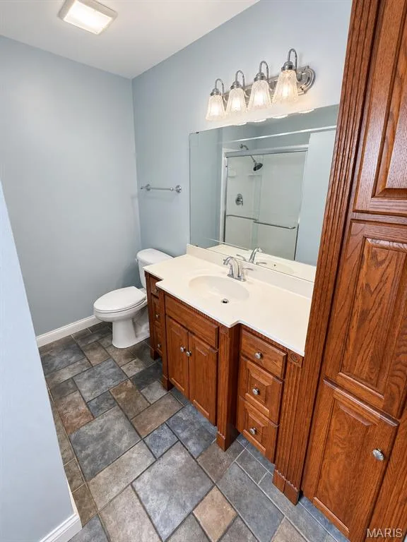 Integrated vanity with a single basin sink, wood-finish cabinetry, and a large mirror — 3 Fairfax Drive, St Peters, MO 63376