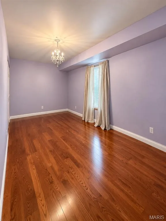 Hardwood flooring, crystal chandelier, window with blinds, and a neutral wall color — 3 Fairfax Drive, St Peters, MO 63376