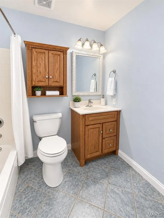Light blue walls with a wall-mounted wooden cabinet, wooden vanity with an integrated sink, polished chrome faucet, and tiled flooring — 3 Fairfax Drive, St Peters, MO 63376