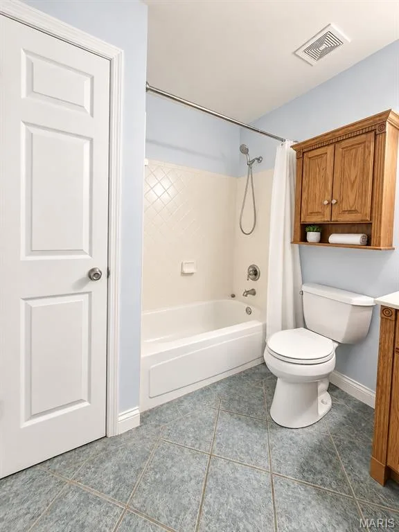 Tiled flooring, white paneled door, built-in wooden cabinetry, white bathtub, and white toilet — 3 Fairfax Drive, St Peters, MO 63376