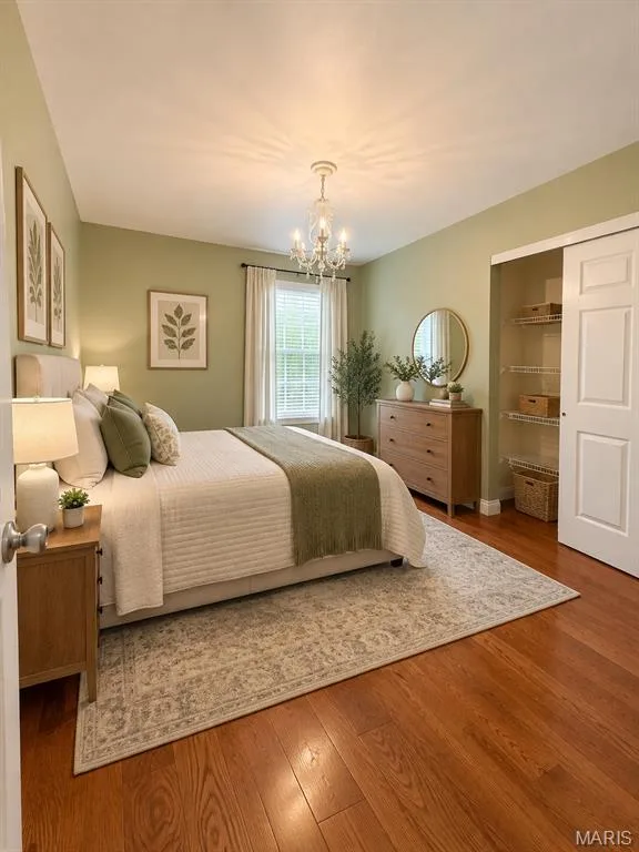 Warm wood-finish flooring, a crystal chandelier, and a window with blinds, virtually staged — 3 Fairfax Drive, St Peters, MO 63376
