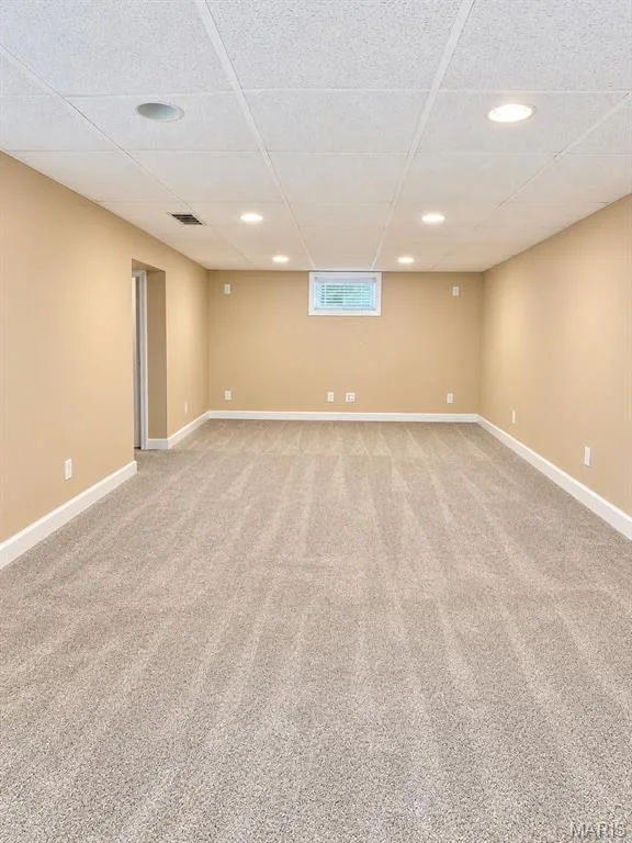 Downstairs living room featuring recessed lighting, a drop ceiling, beige wall paint, white trim, and light-toned carpeting — 3 Fairfax Drive, St Peters, MO 63376