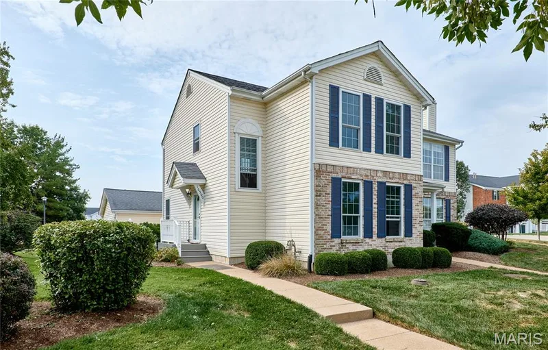 Colonial-style residence featuring cream-colored vinyl siding with stone accents, black shutters, and a peaked roofline with gable detailing — 16500 Victoria Crossing Drive, Wildwood, MO 63040