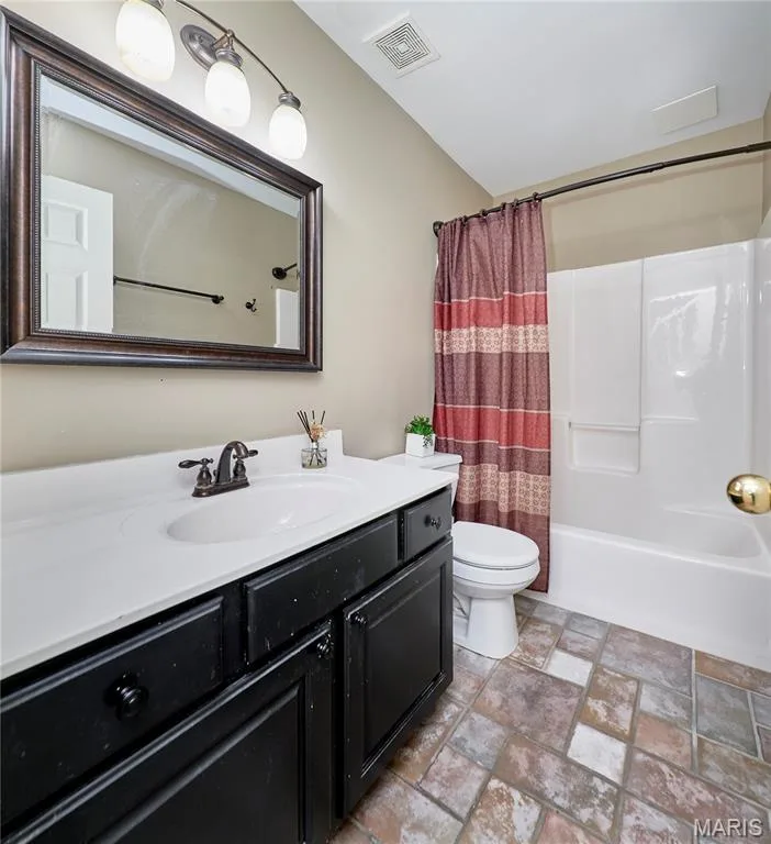 Bathroom featuring a white integrated sink, dark wood-finish vanity, framed mirror, and a full bathtub with a shower — 16500 Victoria Crossing Drive, Wildwood, MO 63040