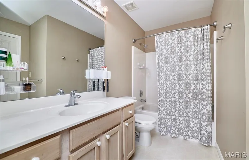 Vanity with integrated sink, chrome-finish faucet, and warm-toned cabinetry — 16500 Victoria Crossing Drive, Wildwood, MO 63040
