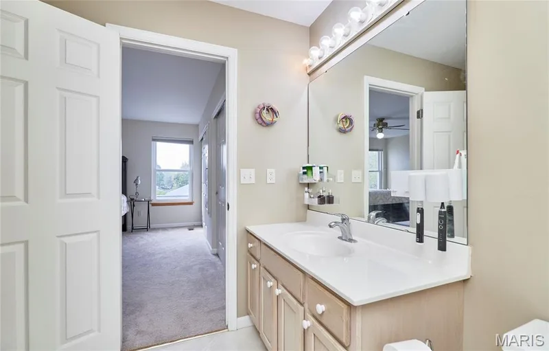 Single vanity with an integrated sink, polished chrome faucet, and expansive wall-mounted mirror — 16500 Victoria Crossing Drive, Wildwood, MO 63040