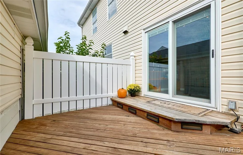 Wood-finish decking with built-in step lighting, white vinyl privacy fence, and sliding glass door — 16500 Victoria Crossing Drive, Wildwood, MO 63040