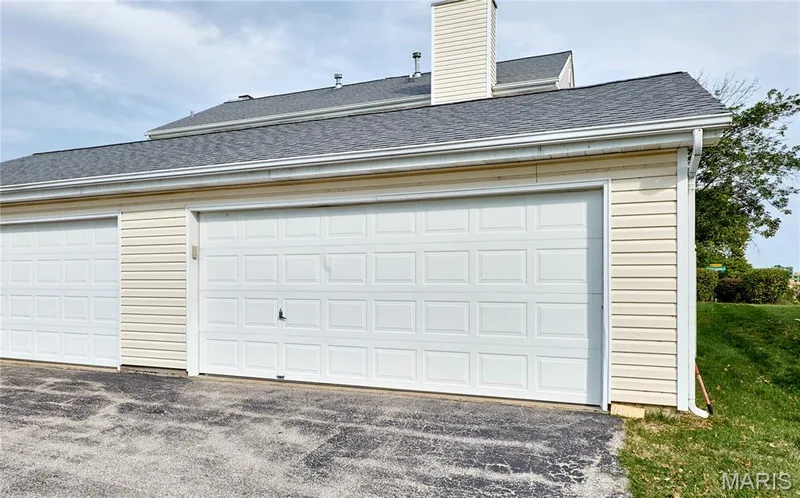 Attached two-car garage featuring panel doors and light-toned siding — 16500 Victoria Crossing Drive, Wildwood, MO 63040