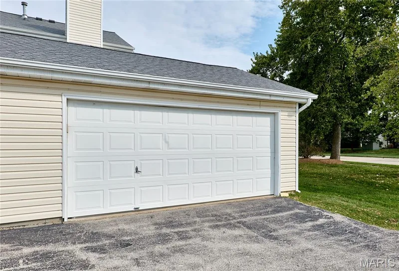 Attached two-car garage with paneling, asphalt shingle roof, and vinyl siding — 16500 Victoria Crossing Drive, Wildwood, MO 63040