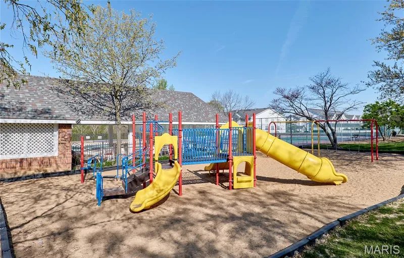 Playground featuring multiple slides, climbing structures, and swings, set on a sand base — 16500 Victoria Crossing Drive, Wildwood, MO 63040