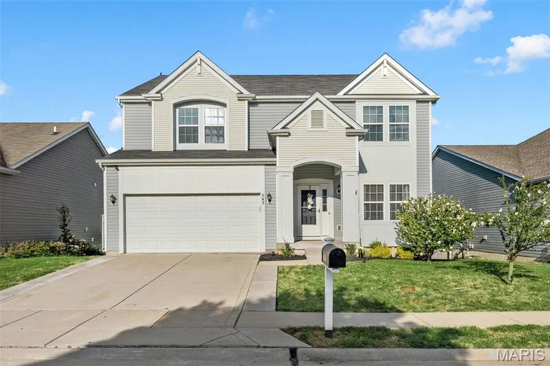 Two-story exterior with a covered front entry, attached two-car garage, multiple gables, and mature landscaping — 543 Country Chase Drive, Lake St. Louis, MO 63367
