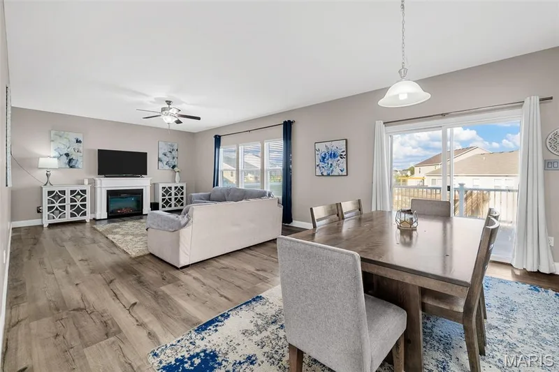 Open-concept living and dining area featuring wood-finish flooring, a built-in fireplace, and a ceiling fan — 543 Country Chase Drive, Lake St. Louis, MO 63367