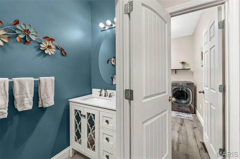 Vanity with integrated sink, white cabinetry with decorative mirrored fronts, and brushed nickel fixtures — 543 Country Chase Drive, Lake St. Louis, MO 63367