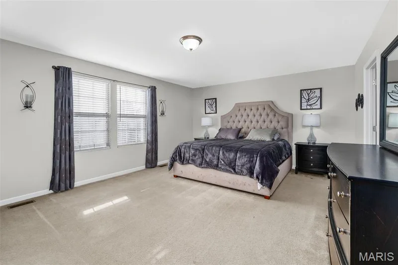 Spacious room featuring neutral carpeting, light gray walls, two windows with blinds, and a ceiling-mounted light fixture — 543 Country Chase Drive, Lake St. Louis, MO 63367
