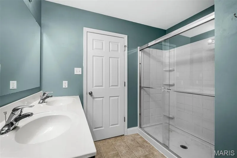 Dual basin vanity, large vanity mirror, glass-enclosed shower, white tile shower surround, and neutral tile flooring — 543 Country Chase Drive, Lake St. Louis, MO 63367
