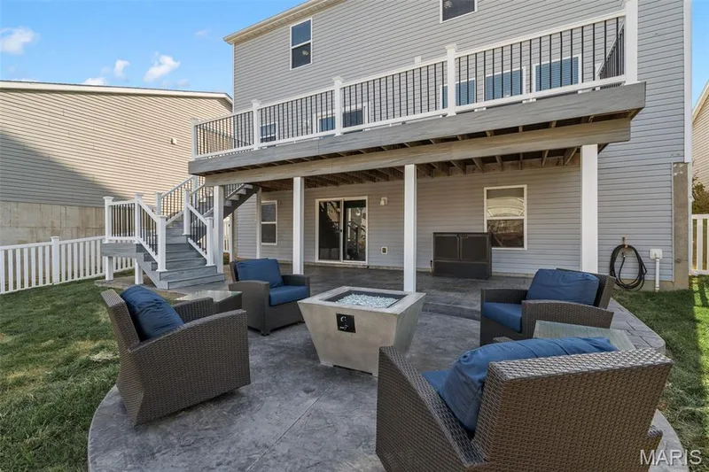 Expansive backyard featuring a stamped concrete patio, concrete fire pit, and a multi-level deck with white and black railings — 543 Country Chase Drive, Lake St. Louis, MO 63367