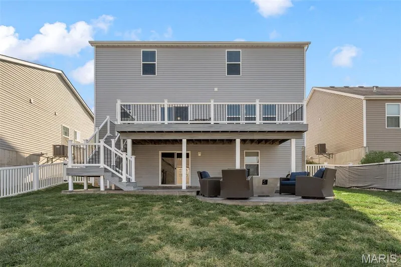 Two-story home with light gray siding, an upper-level deck, lower-level patio, and a fenced yard — 543 Country Chase Drive, Lake St. Louis, MO 63367