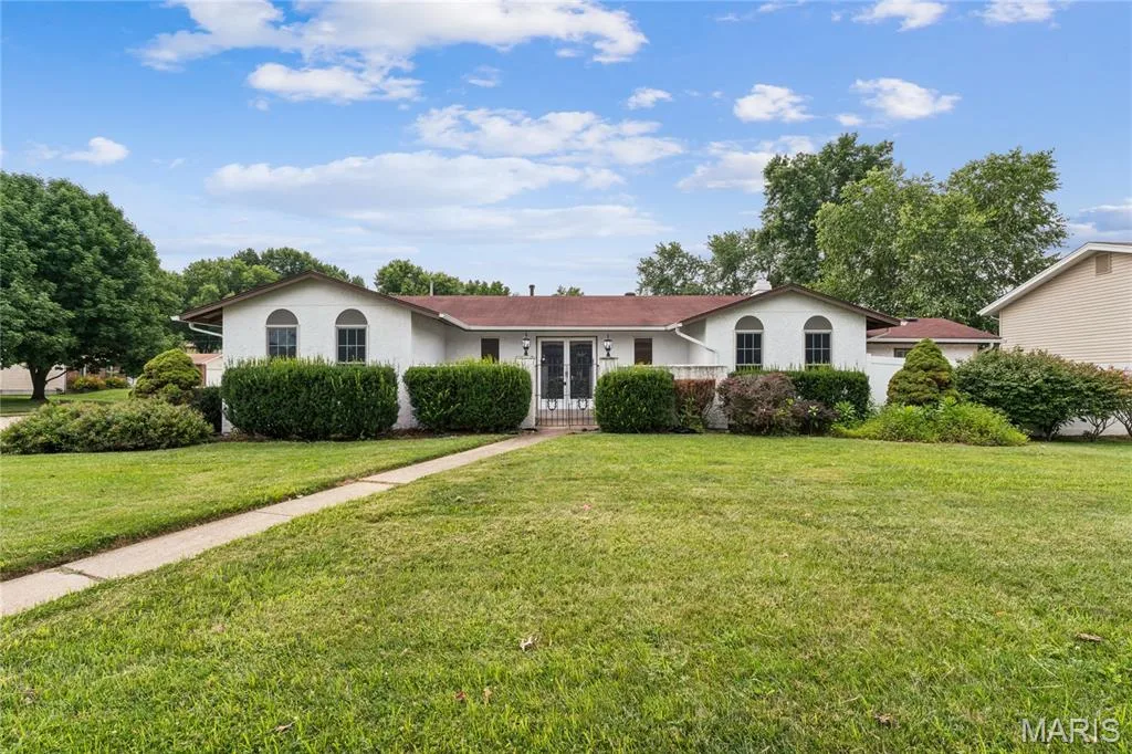 White exterior with arched windows, mature landscaping, and an expansive front lawn — 2801 Droste Road, St Charles, MO 63301