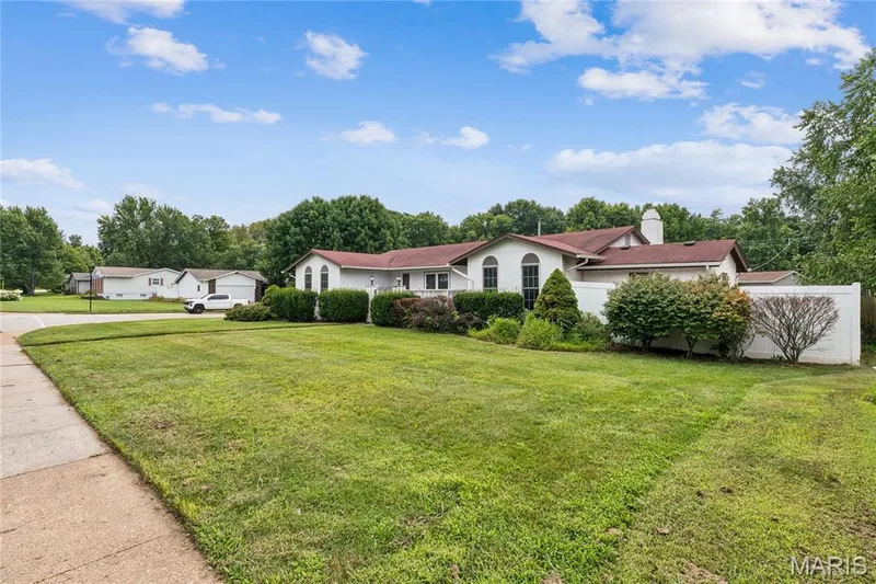 Expansive green lawn, mature landscaping, white privacy fencing, arched windows, and a prominent chimney — 2801 Droste Road, St Charles, MO 63301