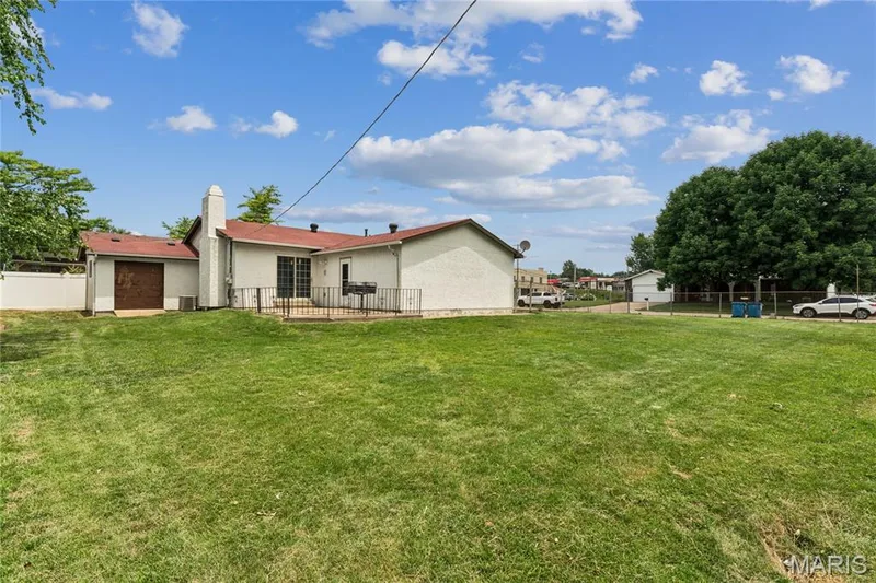 Expansive lawn featuring a patio with black metal railing, sliding glass door access, and exterior door to workshop — 2801 Droste Road, St Charles, MO 63301