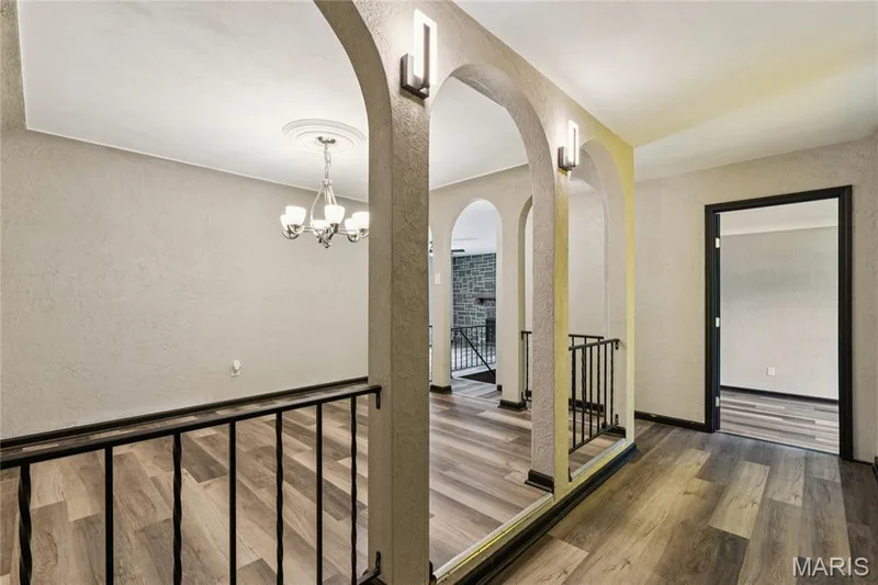 Wood-finish flooring throughout, multiple archways, and a decorative chandelier with ceiling medallion — 2801 Droste Road, St Charles, MO 63301