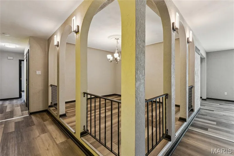 Architectural archways with integrated sconce lighting, wrought iron railing, and wood-finish flooring — 2801 Droste Road, St Charles, MO 63301